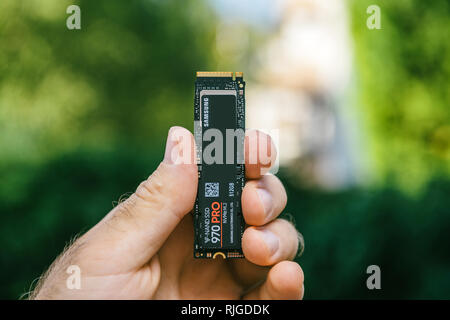 PARIS, FRANCE - JUL 27, 2018: Man hand holding new Samsung 870 Pro NVME PCIE SSD hard drive disk with high read and write speed Samsung 870 Pro - vertical holding ssd nvme Stock Photo