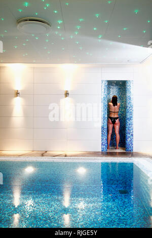 Woman having shower near indoor swimming-pool Stock Photo