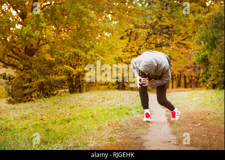 running along a park path, healthcare and problem concept - close-up of an unhappy person suffering from pain in the leg or knee outdoors Stock Photo