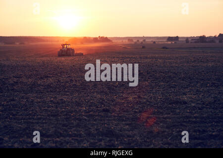 Tractor on field at sunset Stock Photo