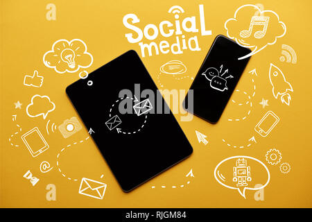 top view of digital tablet and smartphone with social media illustration on yellow background Stock Photo