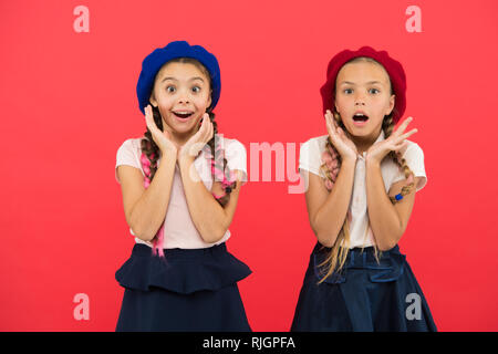 School fashion concept. Surprised girls wear formal uniform red background. International exchange school program. Education abroad. Apply form enter international school. French language school. Stock Photo