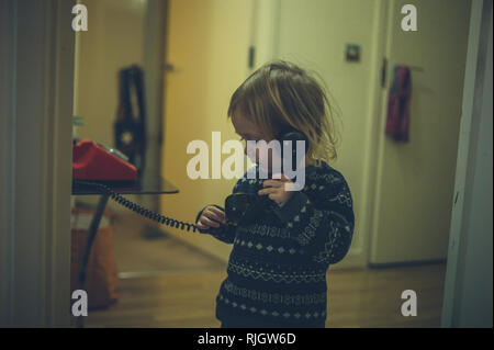 A cute little toddler is talking on an old rotary telephone Stock Photo