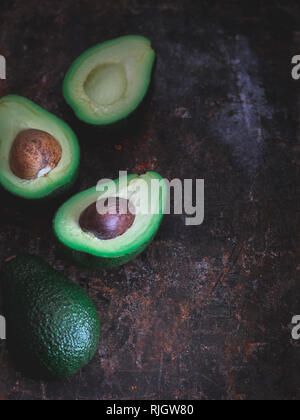 Cut avocados on a dark rustic background, vertical Stock Photo