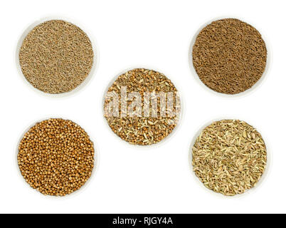 Bread spice mixture in the middle, surrounded by its single ingredients anise, caraway, coriander and fennel seeds in bowls. Stock Photo