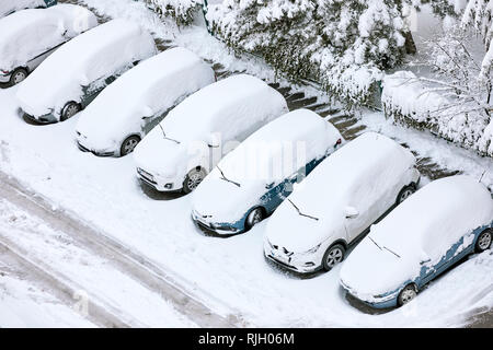 Cars covered with snow with their windshield wipers lifted in a parking lot in winter Stock Photo