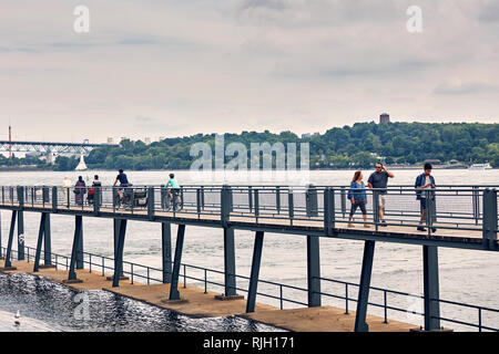 Montreal, Canada - June, 2018: Mixed race people walking on the pedestrian footbridge over saint lawrence river in Old Montreal Port area in summer, Q Stock Photo