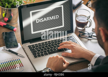 Disarmed concept. Man working with a computer, disarmed text on the screen, business, office background Stock Photo