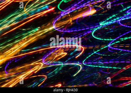 Abstract diagonal glowing multicolored  rounded lines on black background. Photographic effect with long exposure. Stock Photo