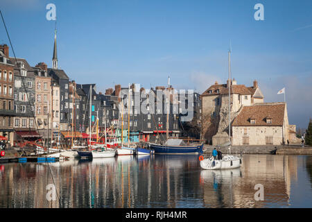 A yacht sails out of the old harbour or Vieux Bassin from St. Catherine's Quay in Honfleur, Normandy, France. Stock Photo