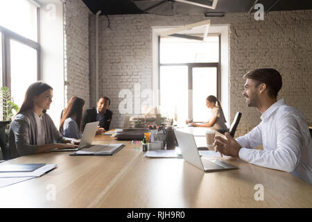 Colleagues sit at coworking table communicating and laughing Stock Photo