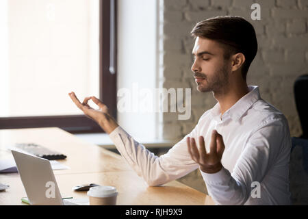 Peaceful worker meditating with eyes closed at office table Stock Photo