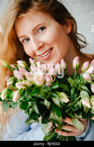 Portrait of a young beautiful girl with a bouquet of roses near window.  Stock Photo