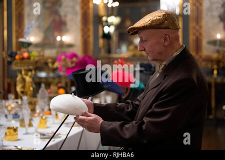 Milliner Stephen Jones adjusts a hat designed for the Duchess of Sussex (2018)at the launch of Chinoiserie-on-Sea exhibition which will fill the rooms of the Royal Pavilion, Brighton, East Sussex, with dozens of hats made by Jones throughout his 40-year career. Stock Photo