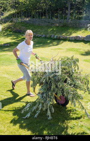 Woman pushing wheelbarrow Stock Photo - Alamy