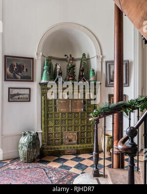 Green glazed stove in the hallway with original black and terracotta tiles Stock Photo