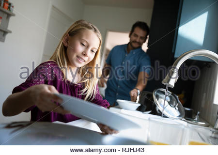 Latinx father and daughter doing dishes at kitchen sink