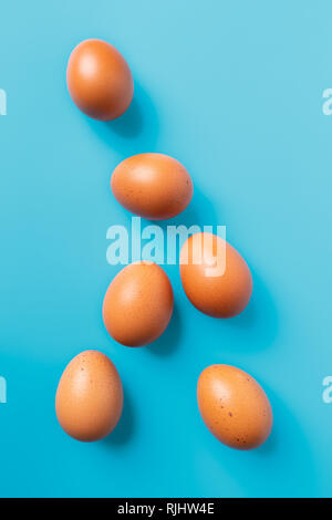 Six brown eggs on blue turquoise background, top view with copy space Stock Photo