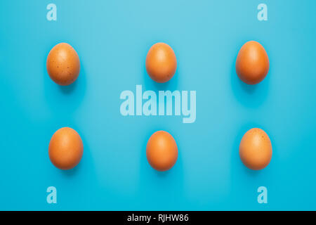 Six brown eggs on blue turquoise background, top view with copy space Stock Photo
