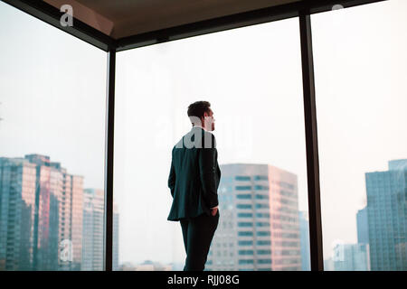 Businessman looking out at city skyline Stock Photo