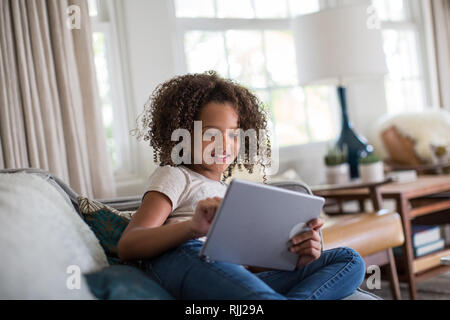 African American girl using digital tablet at home on sofa Stock Photo