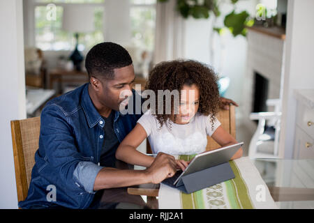 African American father helping daughter with homework using digital tablet Stock Photo