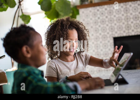 African American brother and sister playing together on digital tablet Stock Photo