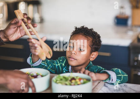 African American boy helping father prepare healthy meal in kitchen Stock Photo