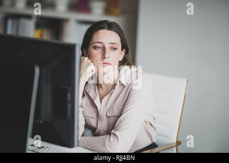 Female business executive in an office looking out of window thinking Stock Photo