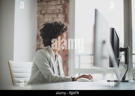 Female african american business executive working in an office on a desktop computer Stock Photo