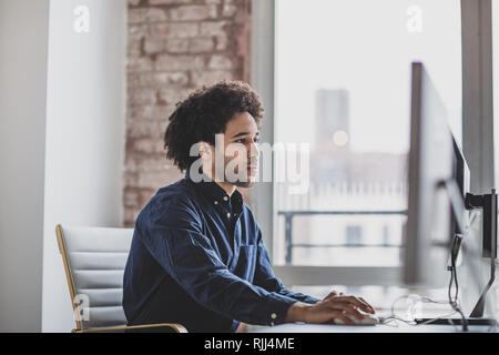 Male african american business executive working in an office on a desktop computer Stock Photo
