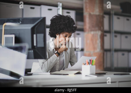 Female african american business executive working in an office looking at paperwork Stock Photo