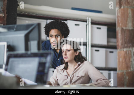 Coworkers looking at a desktop computer together Stock Photo