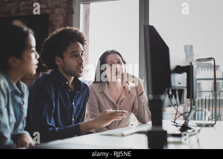 Coworkers looking at a desktop computer together Stock Photo