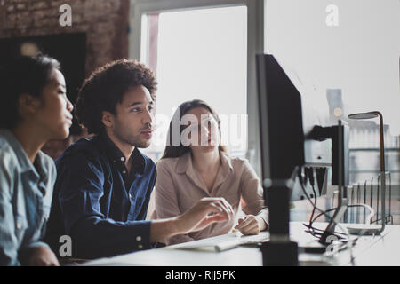 Coworkers looking at a desktop computer together Stock Photo