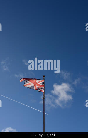 Backlit Union jack flag fluttering in the breeze, with blue sky ...