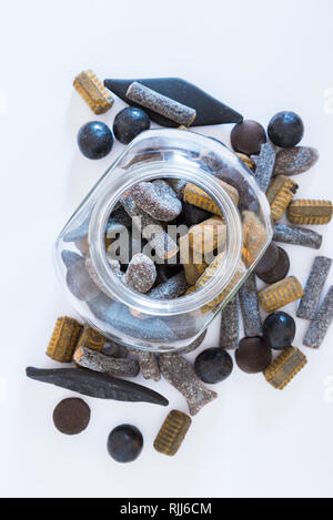 Different varieties of double salted licorice in open glass jar and on white background Stock Photo