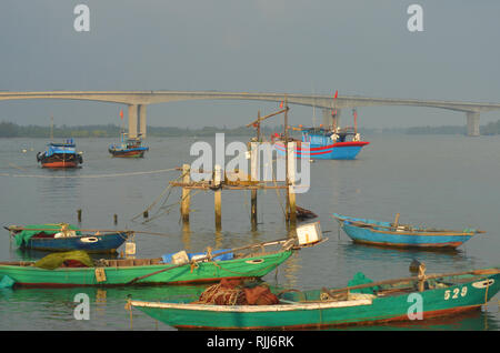 A collection of traditional boats in a harbour in Hoi An, Vietnam. They are painted a range of greens, blues and reds, and have eyes on their prow. A  Stock Photo