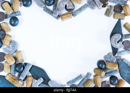 Different varieties of salmiakki arranged in heart-shaped frame on solid white background Stock Photo