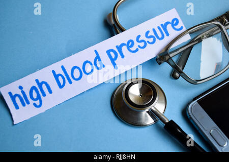 Conceptual image with High blood pressure inscription with the view of stethoscope, eyeglasses and smartphone on the blue background. Medical Conceptu Stock Photo