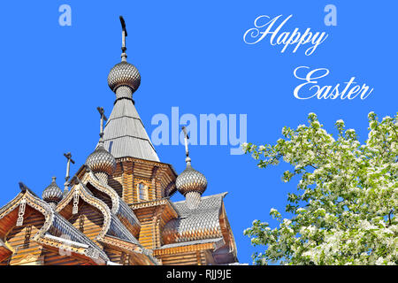 Beautiful Domes and crosses of Christian wooden church and blossoming apple tree with white flowers on a clear blue sky background - spring Easter gre Stock Photo