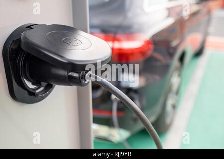 Close up of the power supply plugged into an electric car being charged. Electric car charging station. Concept of environmentally friendly engine Stock Photo