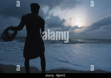 Caption: Allappey, Kerala, India - May 2003. A Keralan fishermen tries his luck in the late afternoon light on a beach outside Appalley, a small town  Stock Photo