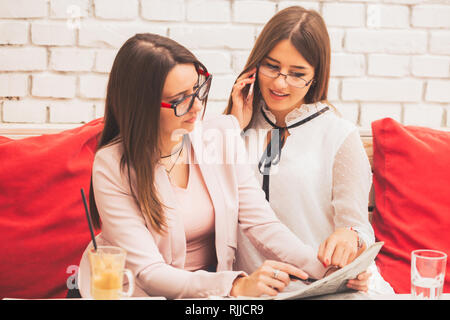 Two young women plan project together, cooperate in preparing for the training of new candidates. Beautiful woman in writes down information while her Stock Photo