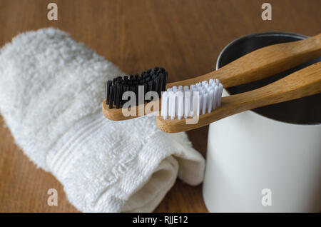 Two Bamboo toothbrushes with white towel on wooden background Stock Photo