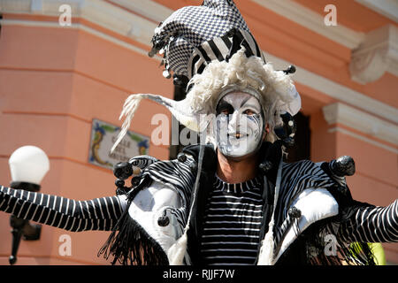 A street theatre performer with a painted face and wild circa costume entertains the crowds on the streets of Havana Vieja Cuba Stock Photo