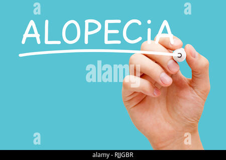 Hand writing Alopecia with white marker on transparent wipe board isolated on blue background. Hair loss or baldness concept. Stock Photo