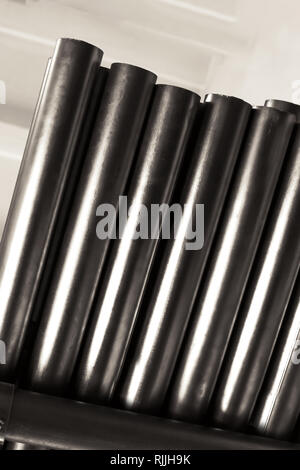 New metal pipes, with chrome plated coating, lie on storage shelves. Concept backgrounds of metal industry Stock Photo