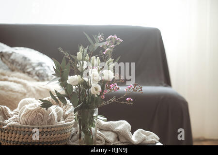 Cozy home interior living room with a black sofa and a vase with flowers and decor items on a small table Stock Photo