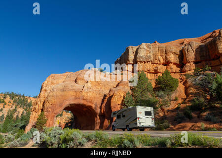 RV cruising through one of the Red Canyon Arches on Utah State Route 12 in the Dixie National Forest in Utah, United States. Stock Photo